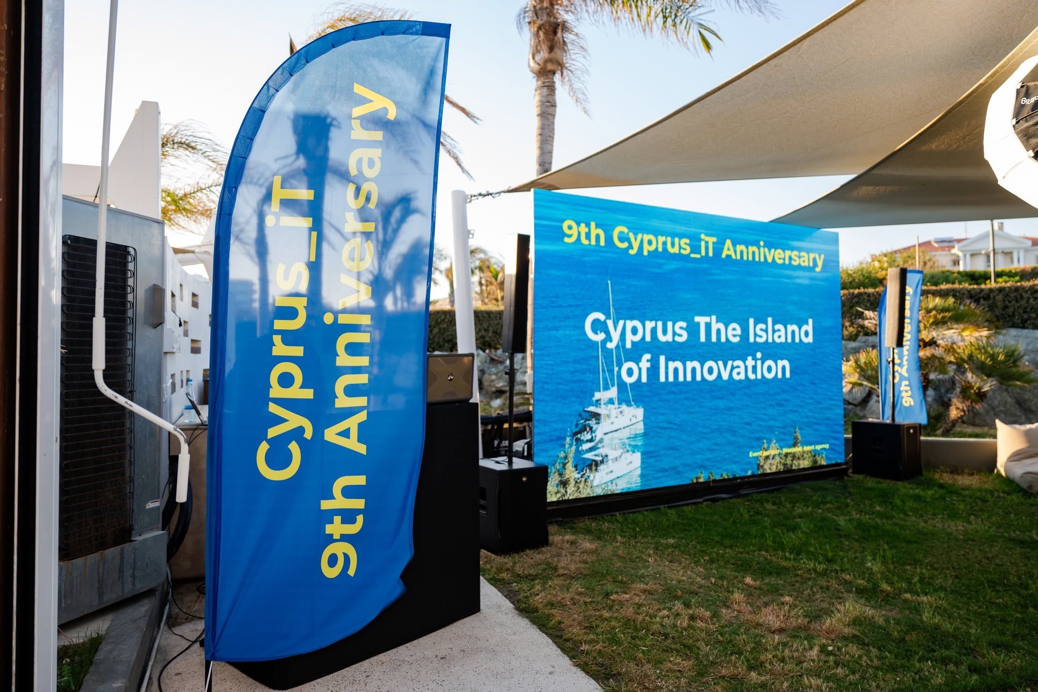 Cyprus_iT ninth anniversary flag beside a screen reading Cyprus — The Island of Innovation
